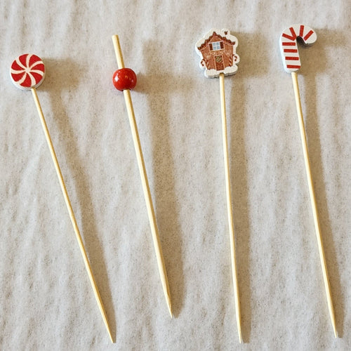 Four wooden skewers with decorative ends on a textured beige background