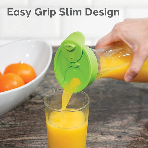 Person pouring orange juice from a carafe with green lid into a glass, with a bowl of oranges in the background.