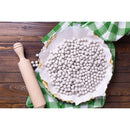 Pie with white paper and pie weights on a wooden table with a rolling pin.