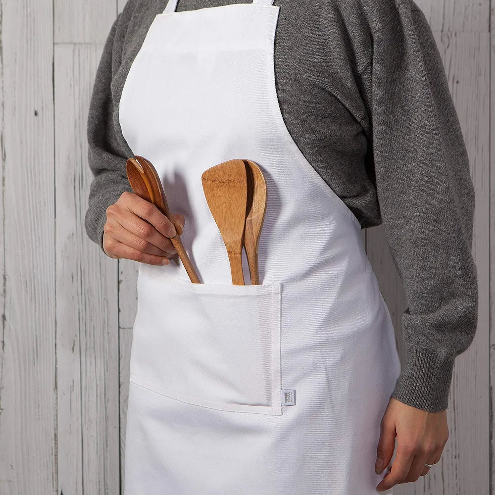 A person wearing a white cotton apron with wooden utensils in the pockets.