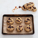 Baked cookies with cherry vanilla jam on a baking tray with parchment paper.