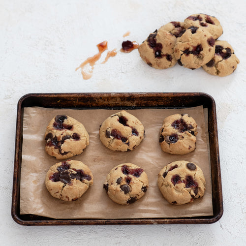 Baked cookies with cherry vanilla jam on a baking tray with parchment paper.