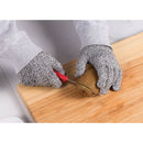 Person cutting a kiwi with a knife on a wooden cutting board, wearing protective gloves.