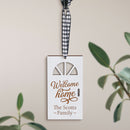A customizable white Christmas ornament hanging by a ribbon. It has text that reads 'Welcome HOME' with a scripted signature-like font, and a space beneath for personalization.