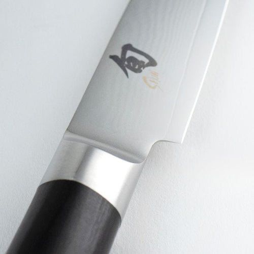 Close-up of a chef's knife with a black handle on a white background