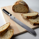Serrated bread knife on a wooden cutting board with sliced bread