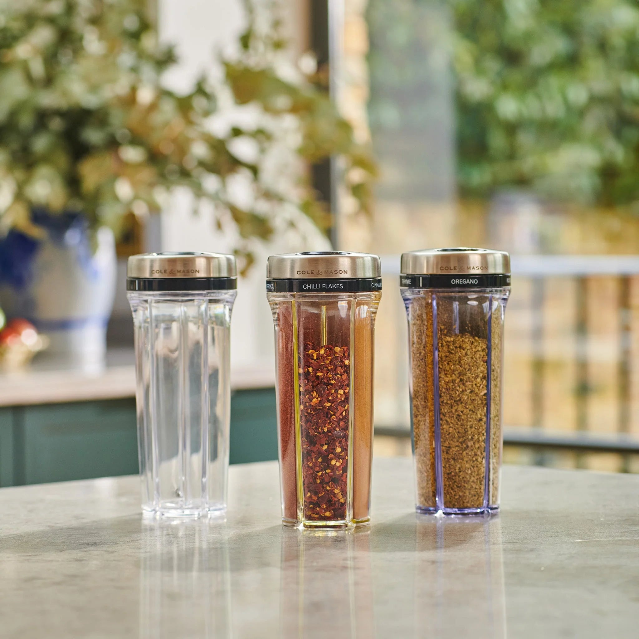 Three spice containers with lids on a kitchen counter