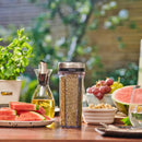 Spice container with rosemary on a table with watermelon and grapes outdoors