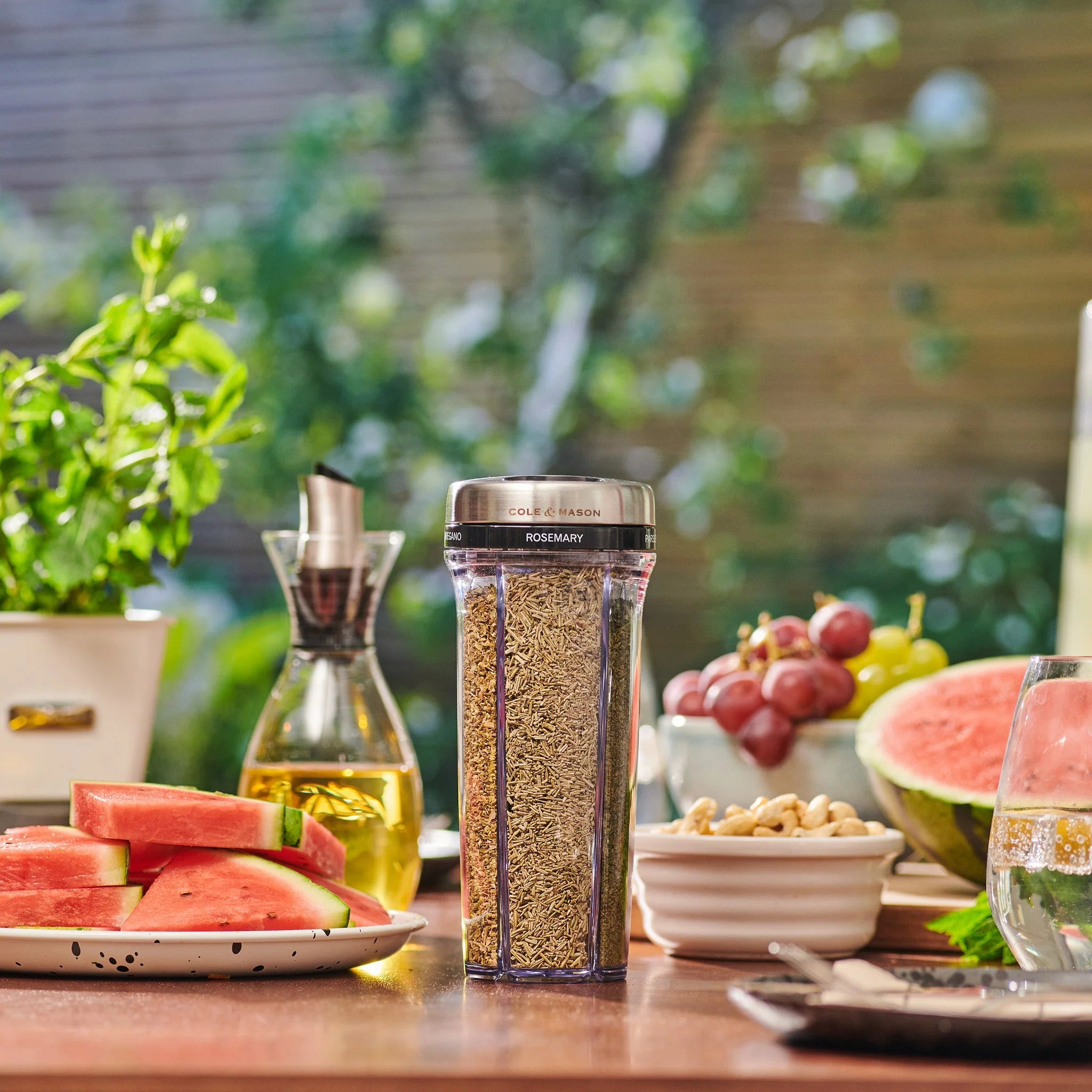 Spice container with rosemary on a table with watermelon and grapes outdoors