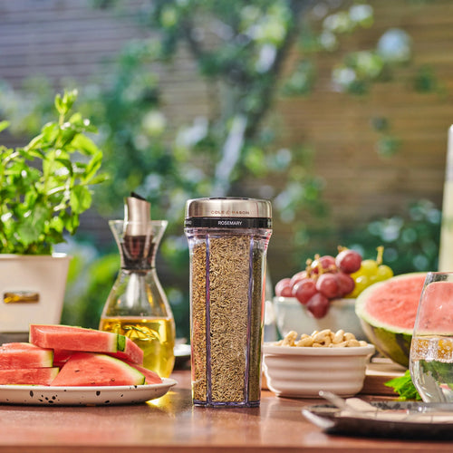 Spice container with rosemary on a table with watermelon and grapes outdoors