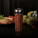 Spice shaker labeled 'Paprika' on a dark surface with blurred background