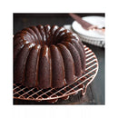 Chocolate bundt cake with a glossy glaze on a copper wire rack.