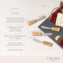 Set of four cheese knives with cork design on a slate board with cheese and berries, featuring Twine Living Co branding.