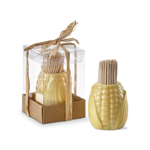 A pale yellow earthenware toothpick holder in the shape of a corn cob, with a group of bamboo toothpicks placed in it. The holder is set against a white background, with another holder with toothpicks beside it inside a clear package with a brown base and a twine bow on top.