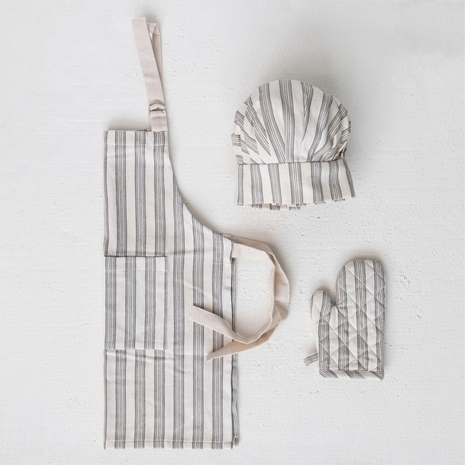 A children's kitchen apron, chef hat, and oven mitt with striped patterns