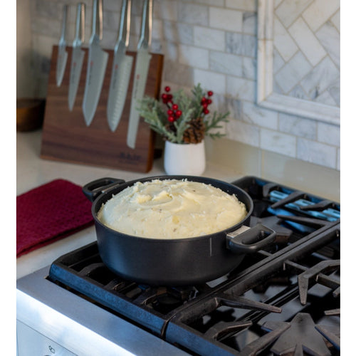 Black pot on a stove with food inside, kitchen setting