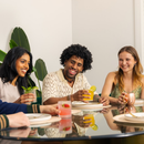 Three people sitting around a table with drinks, smiling and enjoying each other's company.