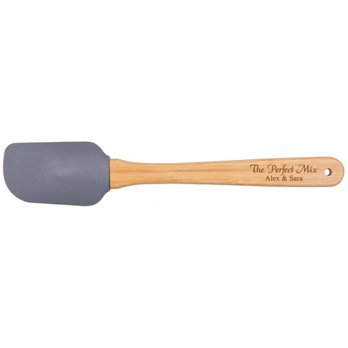 A silicon spatula with a gray head and a beige wooden handle with 'The Perfect Mix' and names 'Alex & Sara' printed on it.