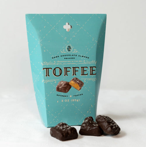 Turquoise package of dark chocolate almond toffee with toffee pieces on a white background