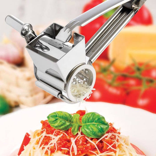 Metal cheese grater grating cheese over fresh pasta on a plate with tomatoes and cheese in the background