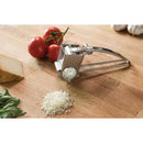 Rotary cheese grater with grated cheese on a wooden surface with tomatoes and basil.
