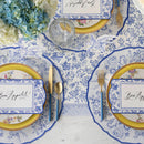 Place settings featuring paper placemats with pheasants and florals in blue and white with blue and gold flatware.