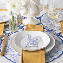 Place settings featuring paper placemats with pheasants and florals in blue and white with blue and gold flatware.