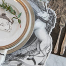 A black and white unicorn illustration as part of a placemat with gold rimmed plates on top.