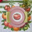 A place setting with tomato placemat, green stripe table runner, gold cutlery, and red checked plates with a tomato shaped name card.