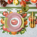 A place setting with tomato placemat, green stripe table runner, gold cutlery, and red checked plates with a tomato shaped name card.