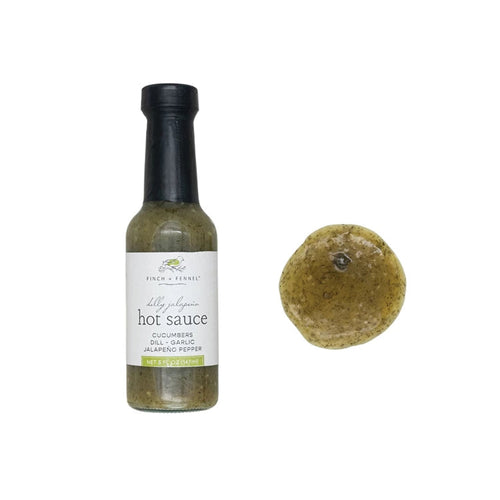 Bottle of hot sauce with a dollop of sauce beside it on a white background