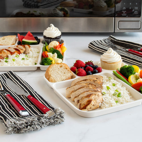 Dinner setup with plates of food, including bread, salad, and desserts, on a kitchen counter.
