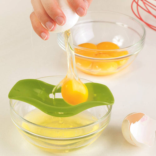 Person using a green egg separator to separate yolks into a glass bowl.