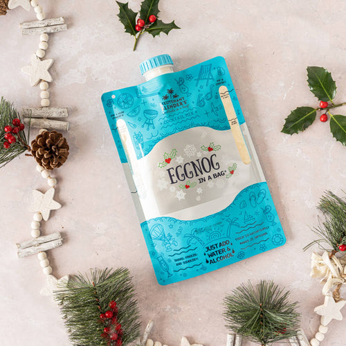Eggnog in a bag packaging with Christmas decorations on a light background