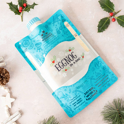 Eggnog in a bag packaging with Christmas decorations on a light background
