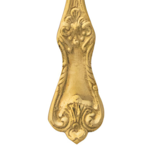 Decorative brass spoon handle on a white background