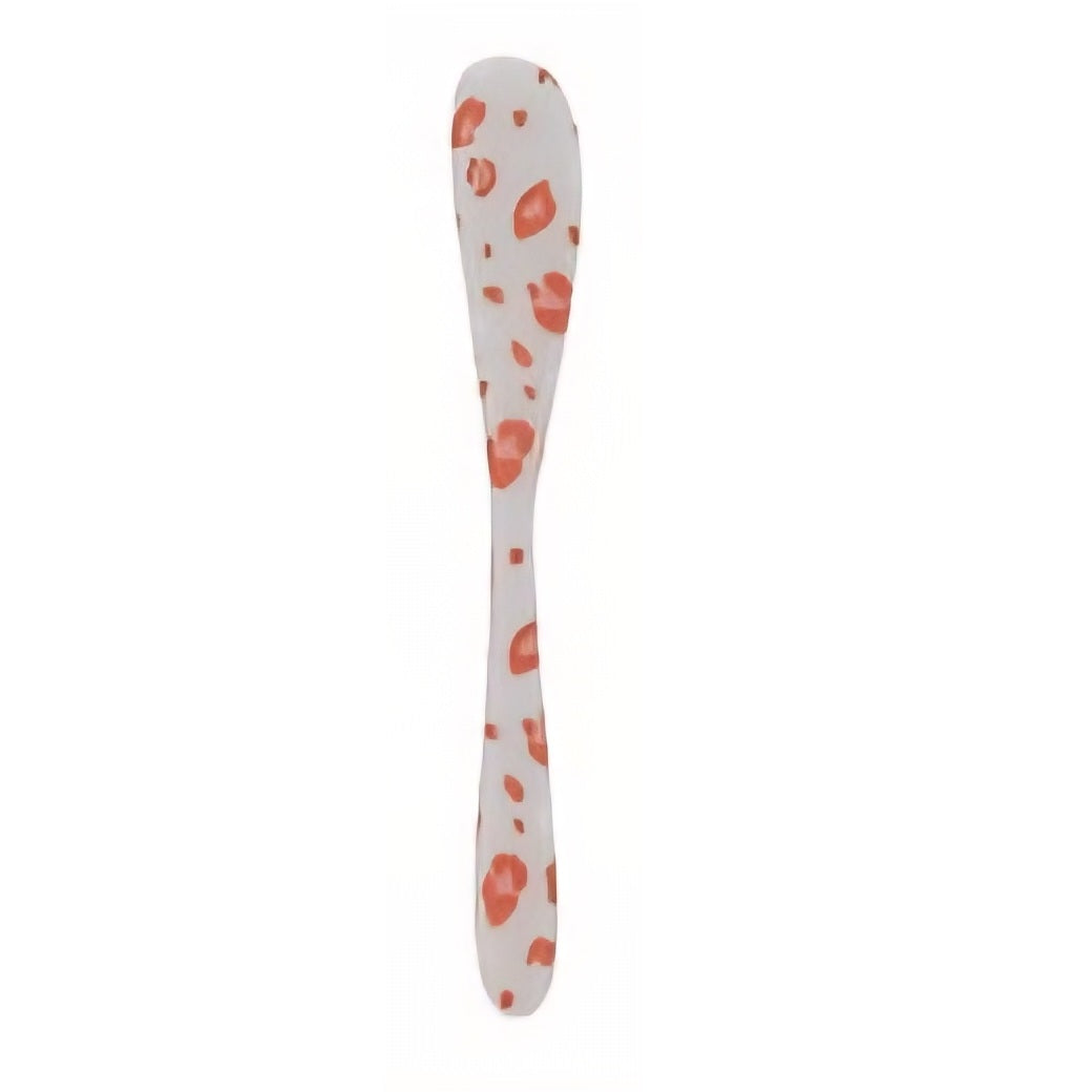 White spoon with orange leopard pattern on a white background