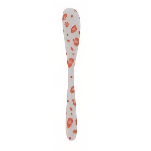 White spoon with orange leopard pattern on a white background