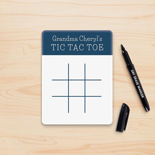 Tic Tac Toe game board with 'Grandma Cheryl's' text on a wooden surface with dry erase markers.