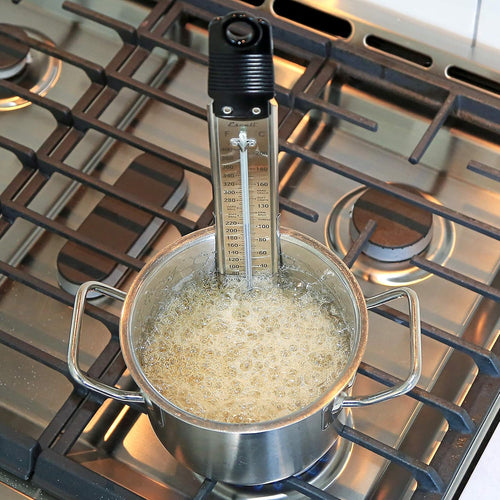 Candy thermometer in a pot of boiling liquid on a stovetop