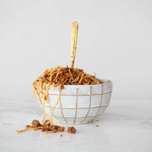 Bowl of spaghetti with a fork on a light gray background