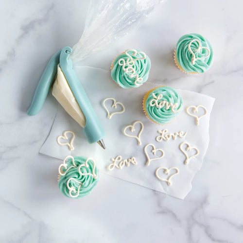 Cupcakes with teal frosting and an icing pen on a marble surface