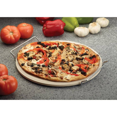 Pizza with various toppings on a stone pizza wheel surrounded by vegetables on a gray surface