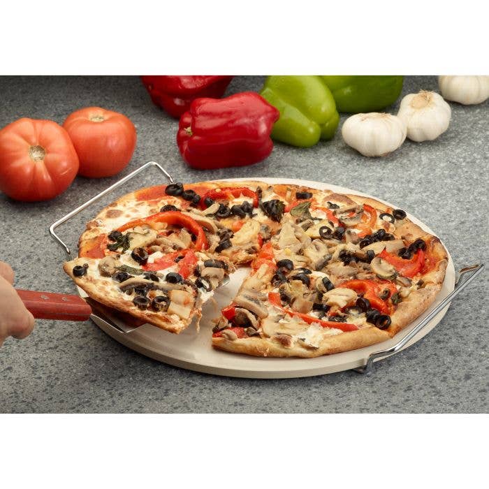 Pizza with various toppings on a stone surface with vegetables