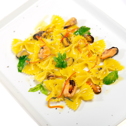 Bowtie pasta with sauce and mussels on a white plate