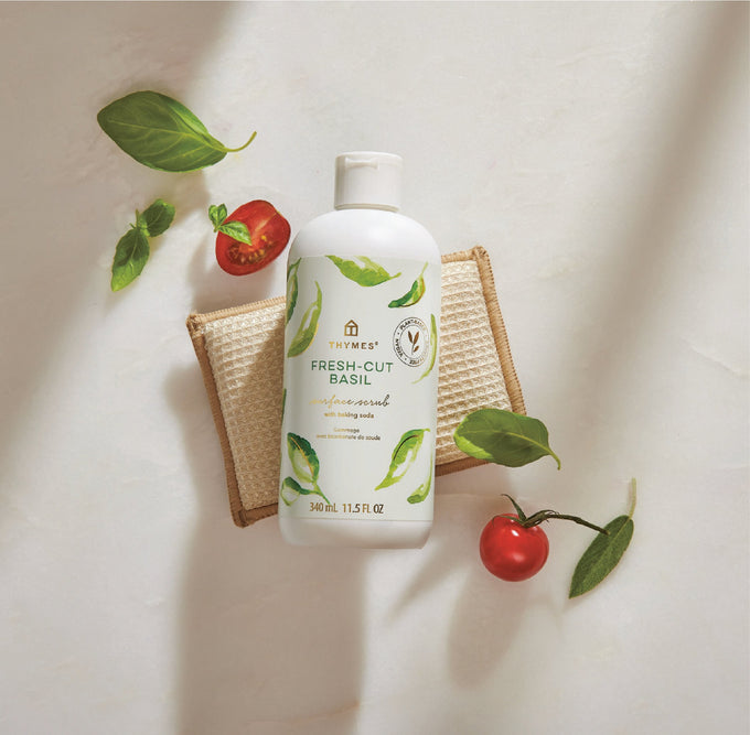 Bottle of Fresh-Cut Basil surface scrub with basil leaves and tomatoes on a light background