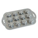 A silver cake pan with snowflake molds on a white background.