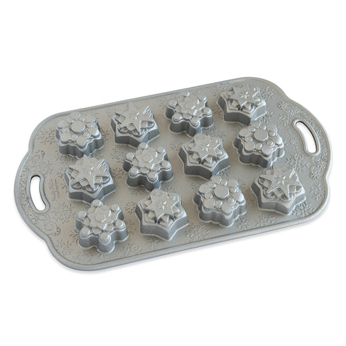 A silver cake pan with snowflake molds on a white background.