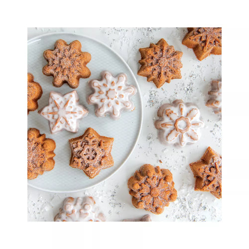 Star-shaped mini cakes on a white plate and surface with a light dusting of powdered sugar.