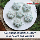 Mini frosted cakes on a plate with greenery and a table linen on a wooden surface with 'bake sensational snowy mini cakes for winter' text beneath it.